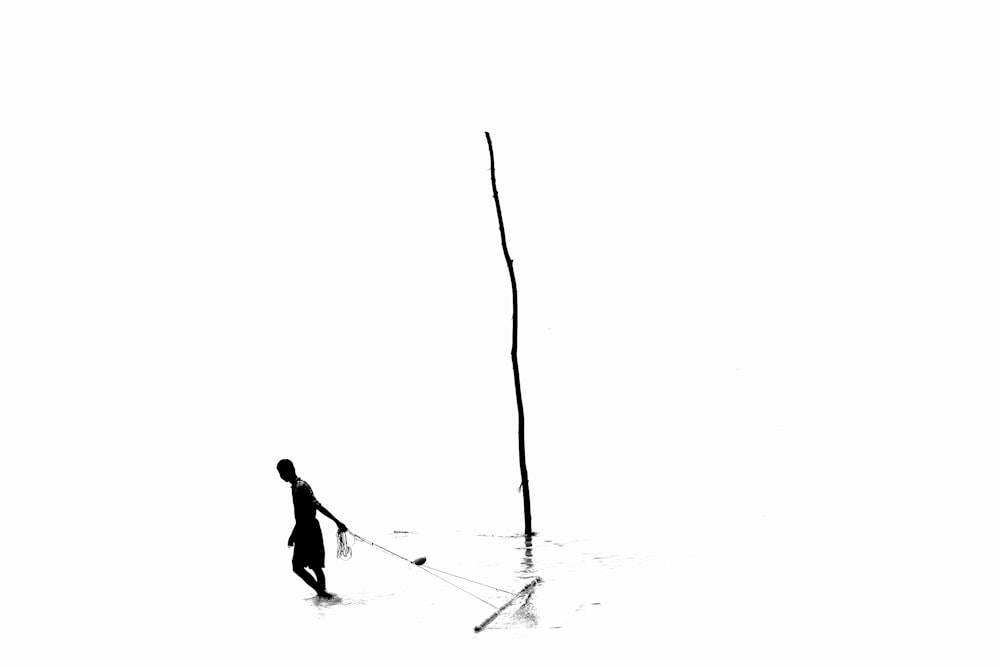 a person standing in a body of water with a pole