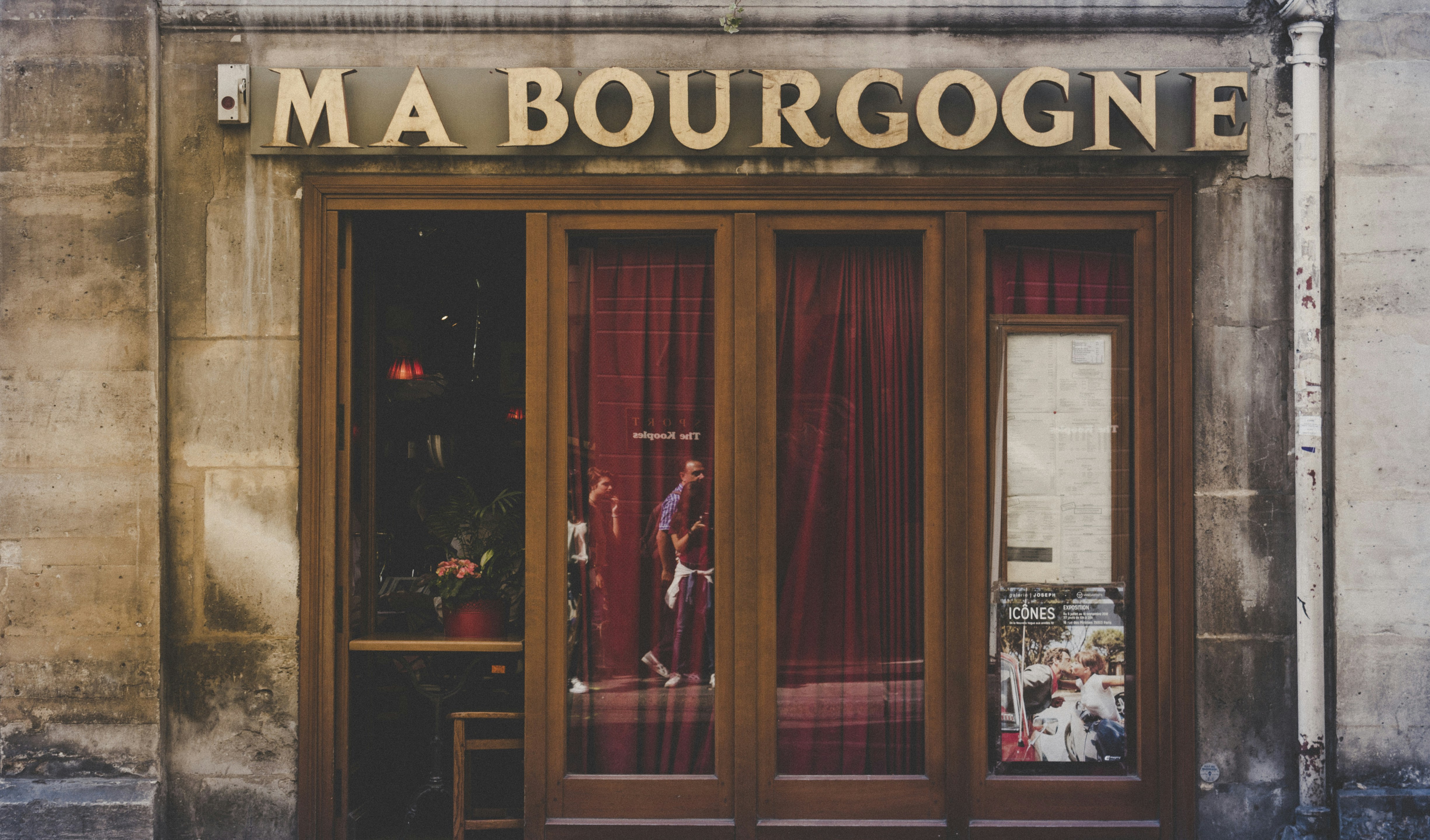 a store front with red curtains and a sign on it