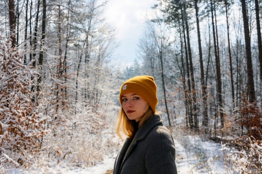 a woman in a yellow hat is standing in the snow