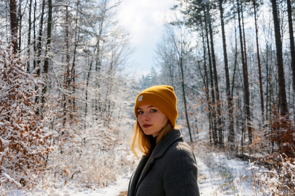 uma mulher em um chapéu amarelo está de pé na neve