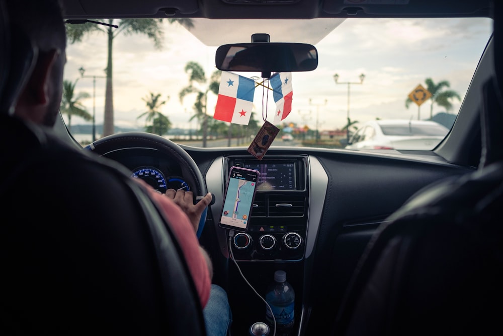 a man driving a car with a flag hanging from the dash