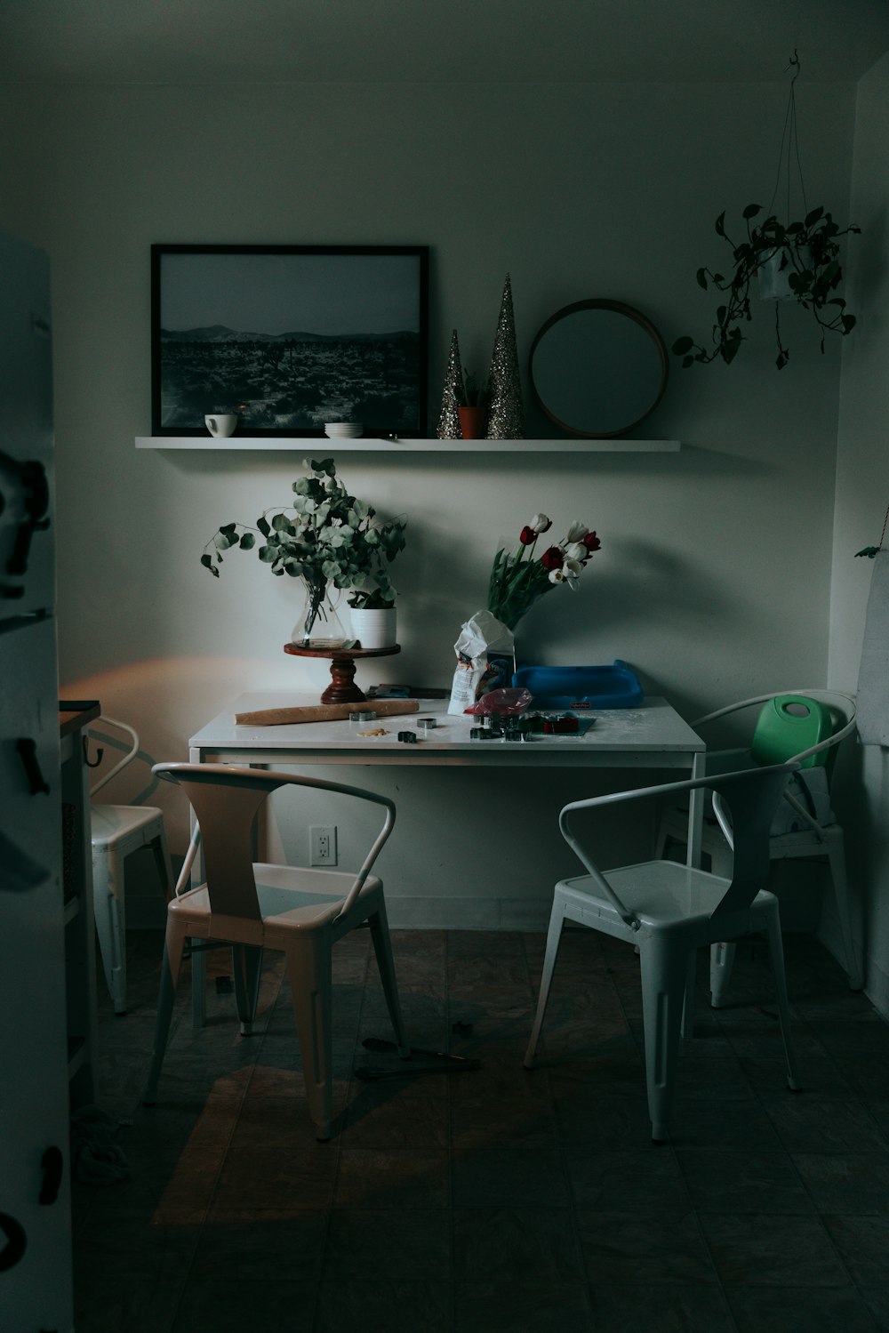 a room with a table, chairs and a shelf with flowers on it