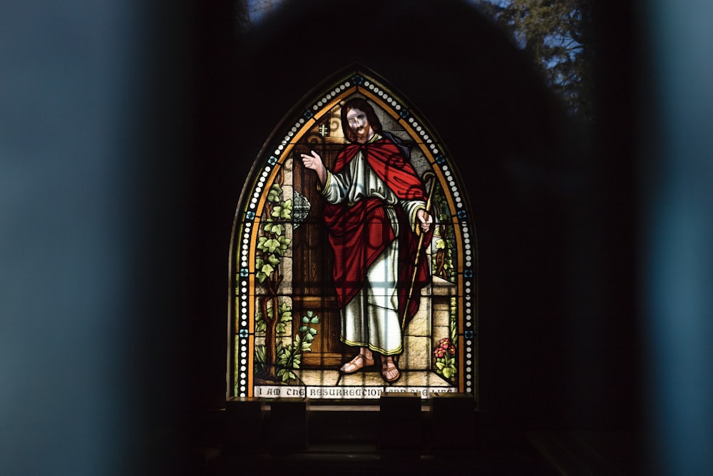 a stained glass window with a person holding a cross