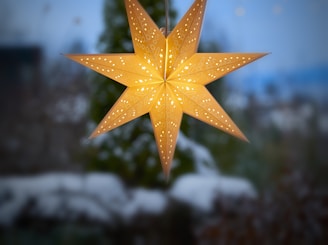 a yellow star hanging from a string on a window