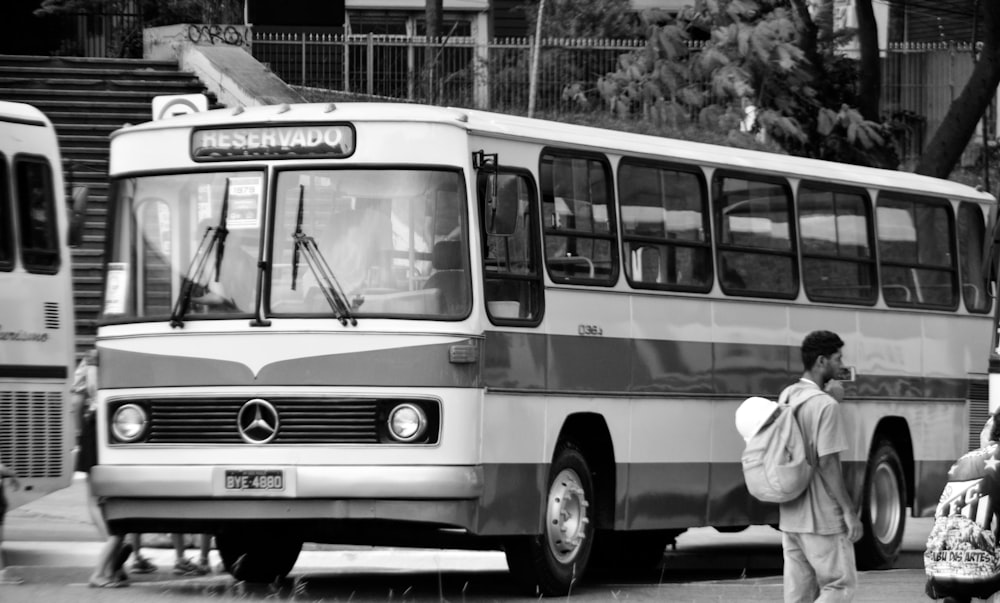 a black and white photo of a bus and people