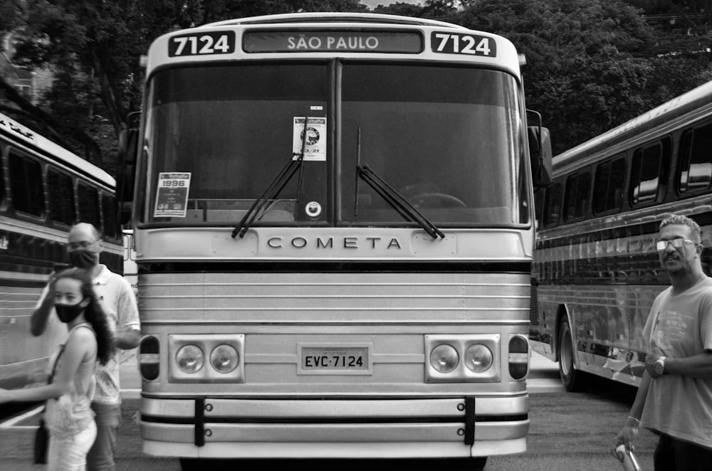 a black and white photo of people standing in front of a bus