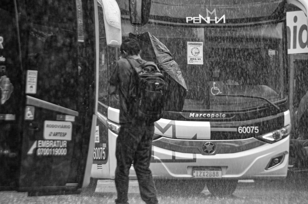 a man standing in front of a bus in the rain