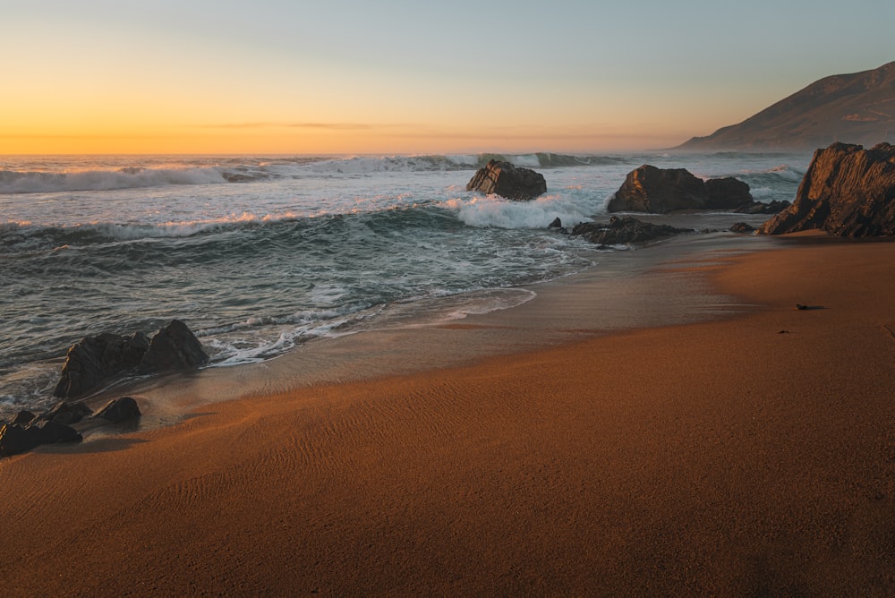 a sandy beach with waves coming in to shore