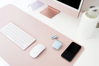 Modern gadgets and sleek electronics with soft pink accents arranged on a clean desk.