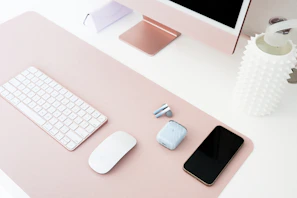 Modern gadgets and sleek electronics with soft pink accents arranged on a clean desk.