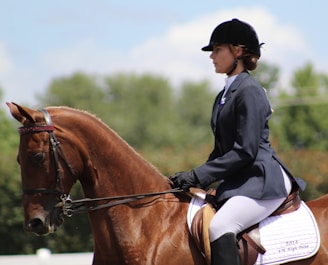 a woman riding on the back of a brown horse