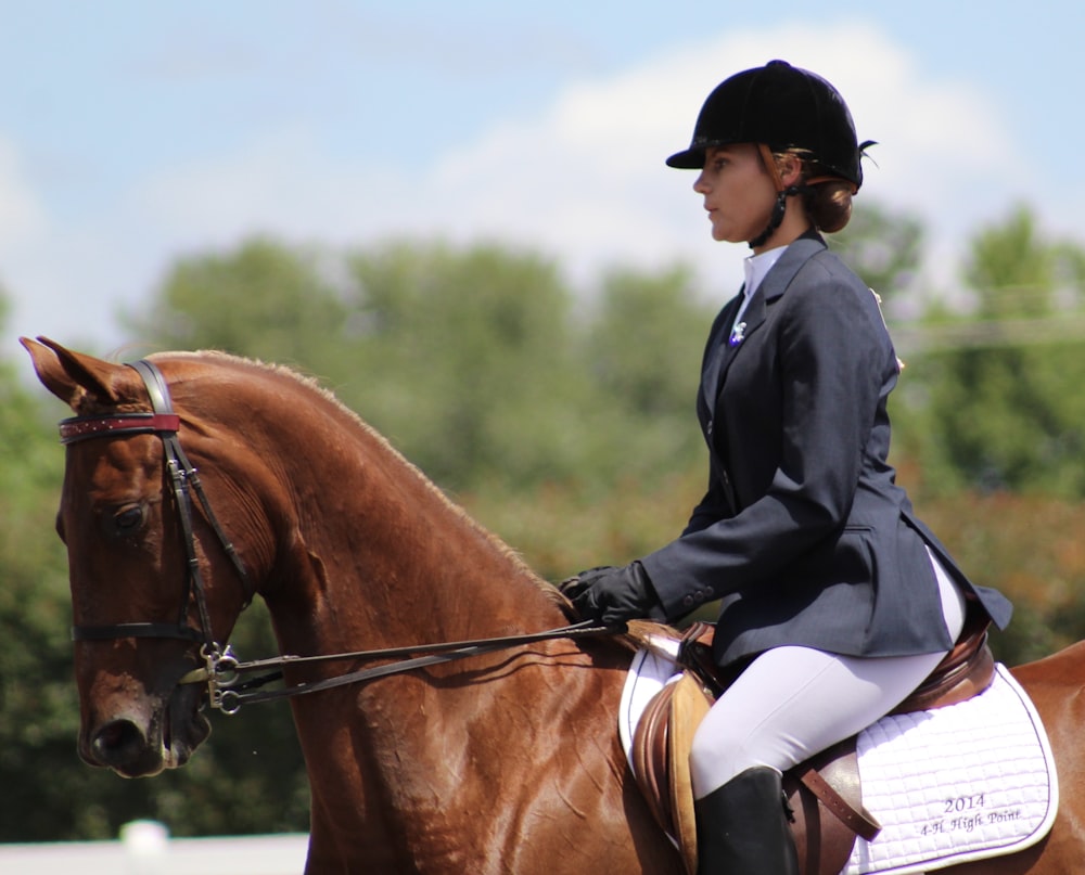 a woman riding on the back of a brown horse