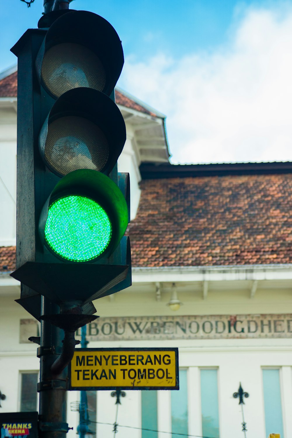 a traffic light with a green light in front of a building