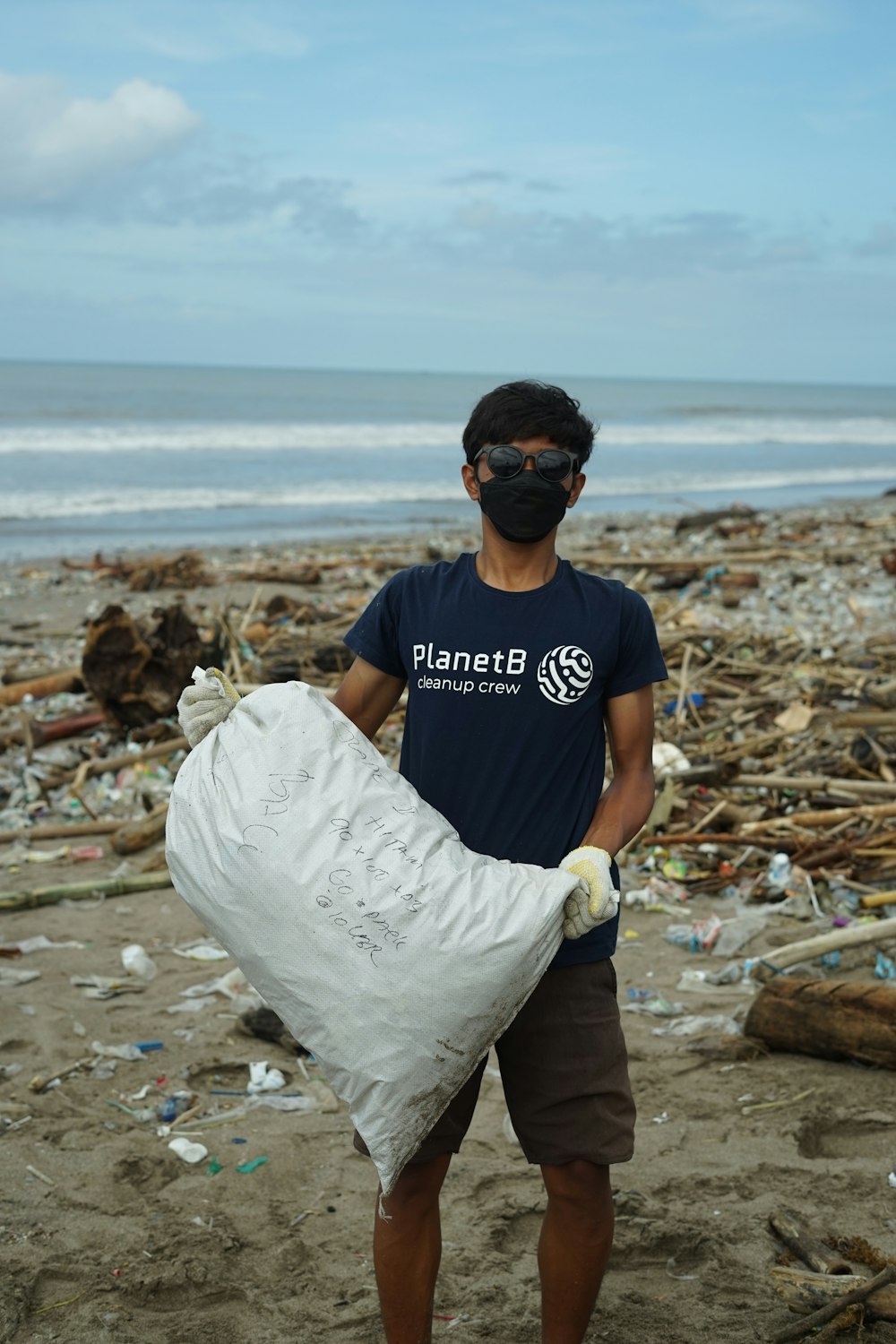 a man holding a bag of garbage on a beach