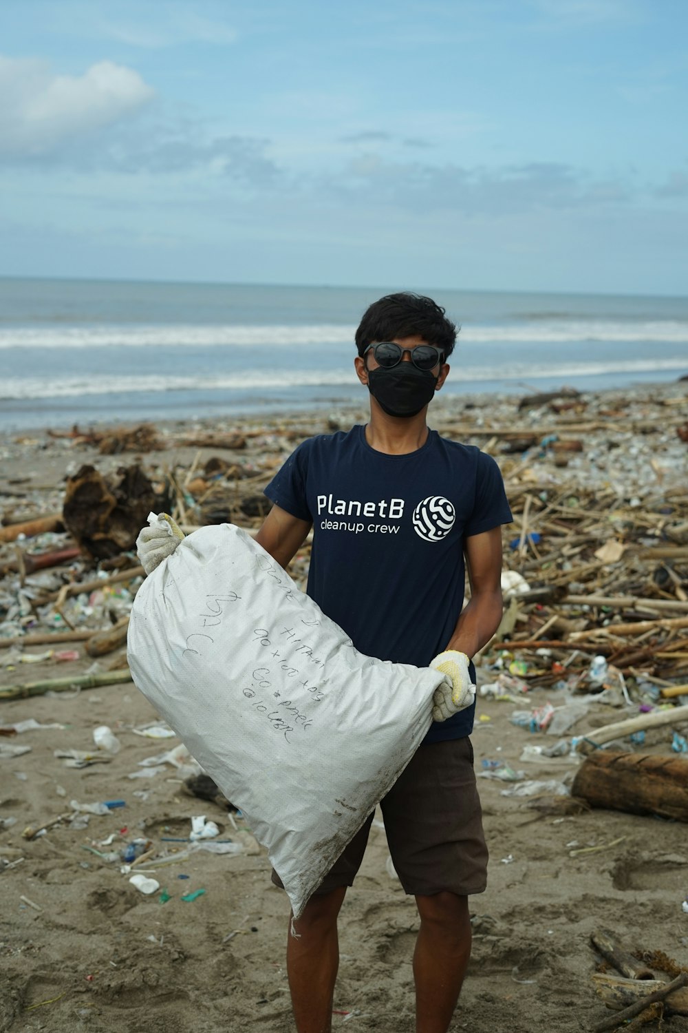 Un homme tenant un sac d’ordures sur une plage