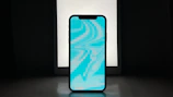 A futuristic smartphone with holographic display glowing in blue and red tones on a dark background.