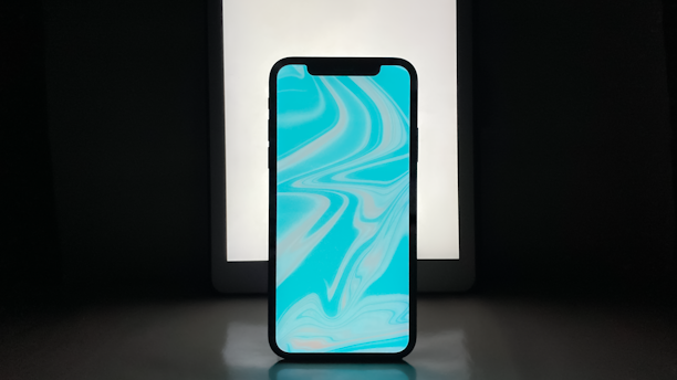 A sleek smartphone glowing with neon blue and purple light, displaying a voice wave interface.