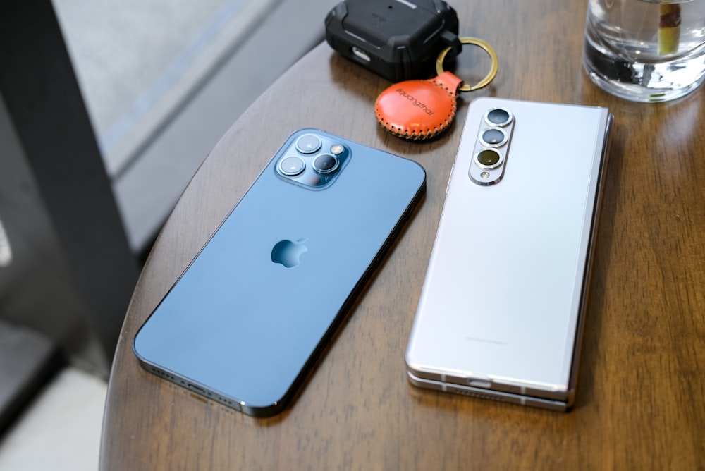 two cell phones sitting on top of a wooden table