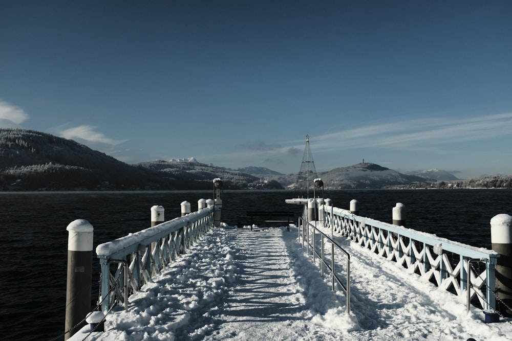 a snow covered pier with mountains in the background