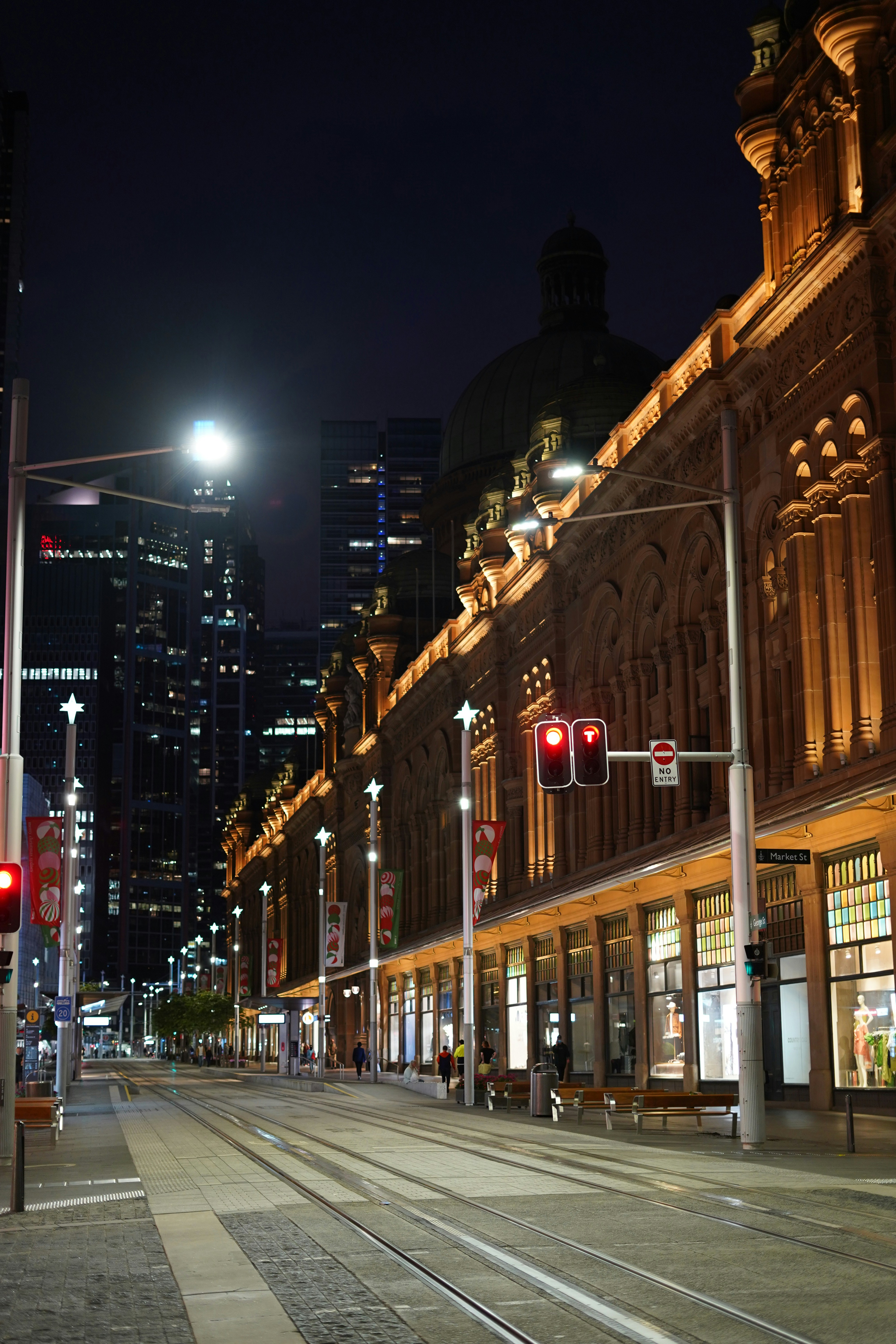 a city street at night with a train on the tracks