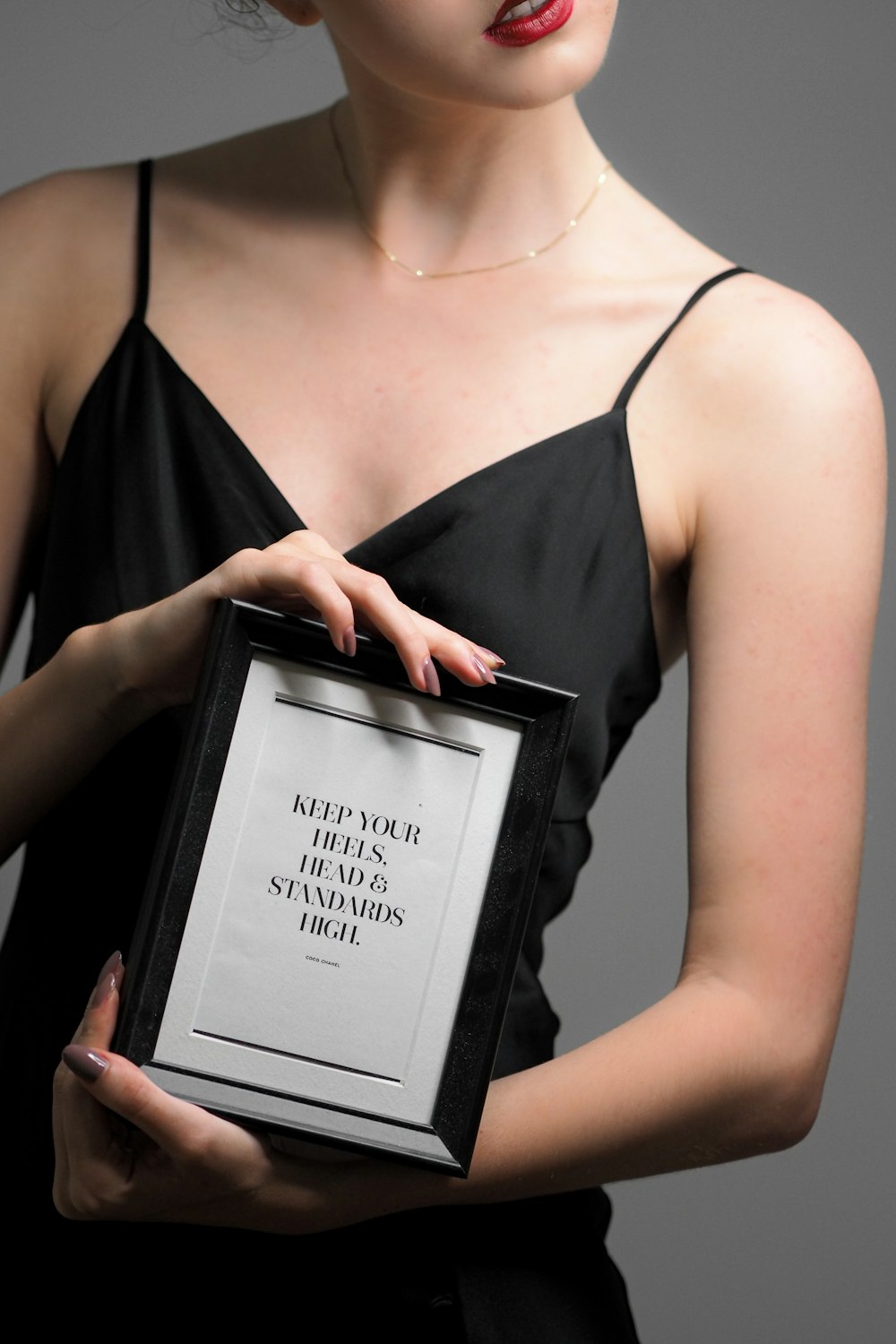 a woman in a black dress holding a framed picture