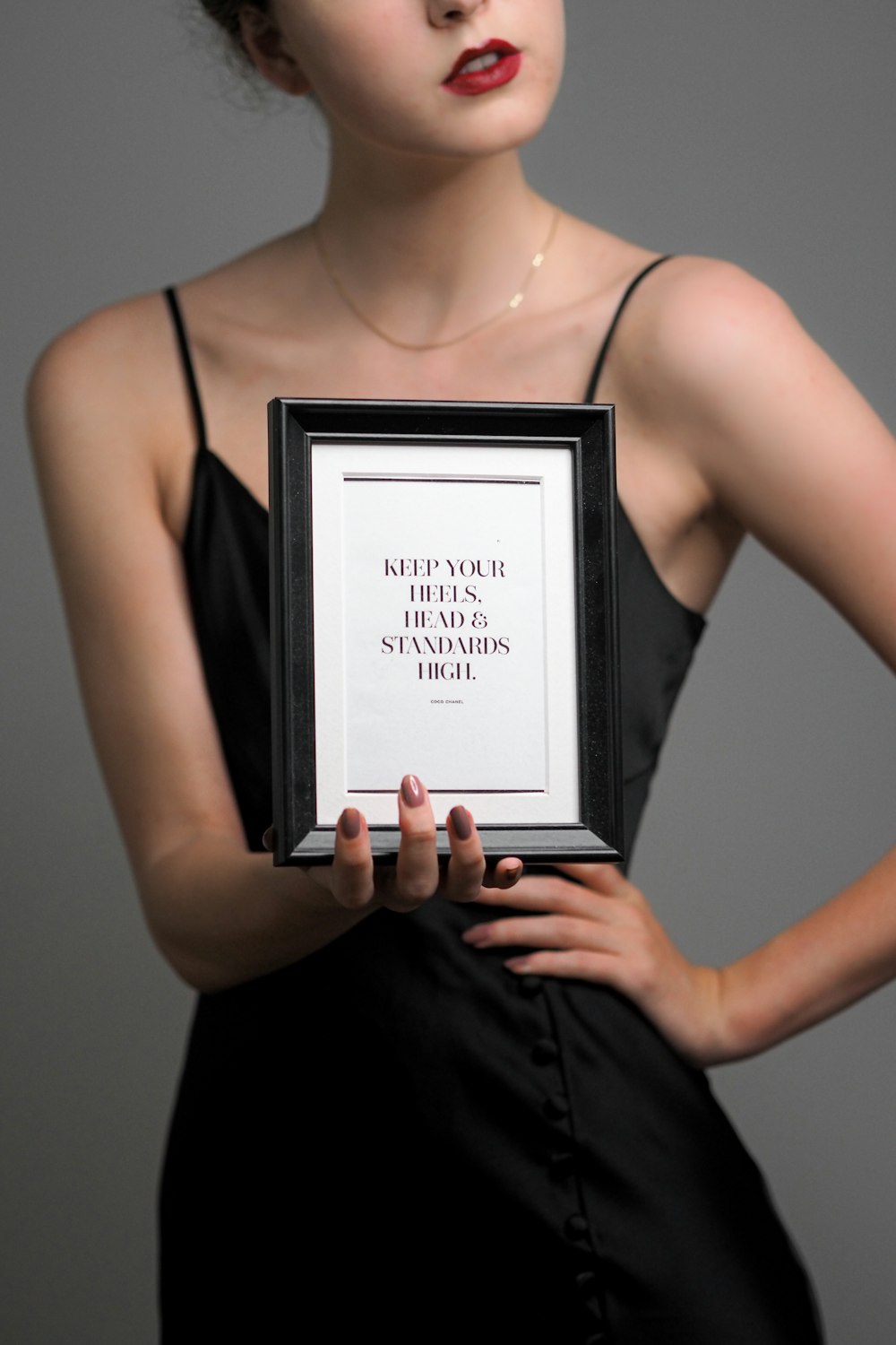 a woman in a black dress holding a framed picture
