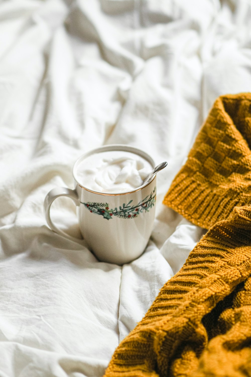 a blanket and a cup of coffee on a bed