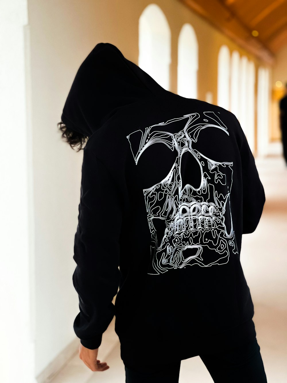 a person wearing a black hoodie with a white skull on it