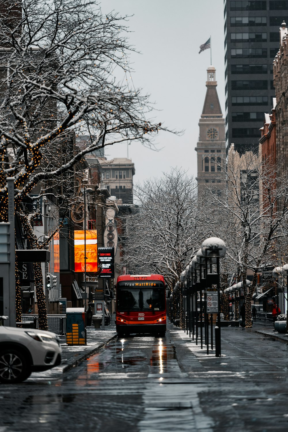 a red bus driving down a street next to tall buildings