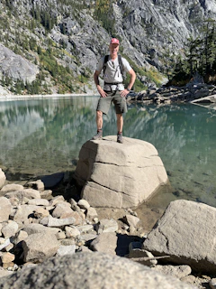 A professional portrait of an industrial engineer in outdoor gear, standing confidently near a canyon.