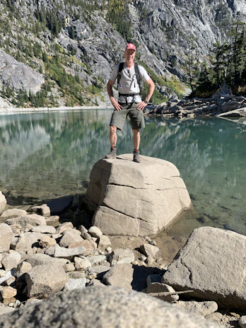 A professional portrait of an industrial engineer in outdoor gear, standing confidently near a canyon.