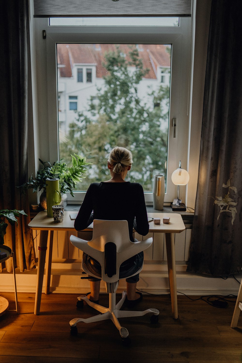 a woman sitting at a desk in front of a window