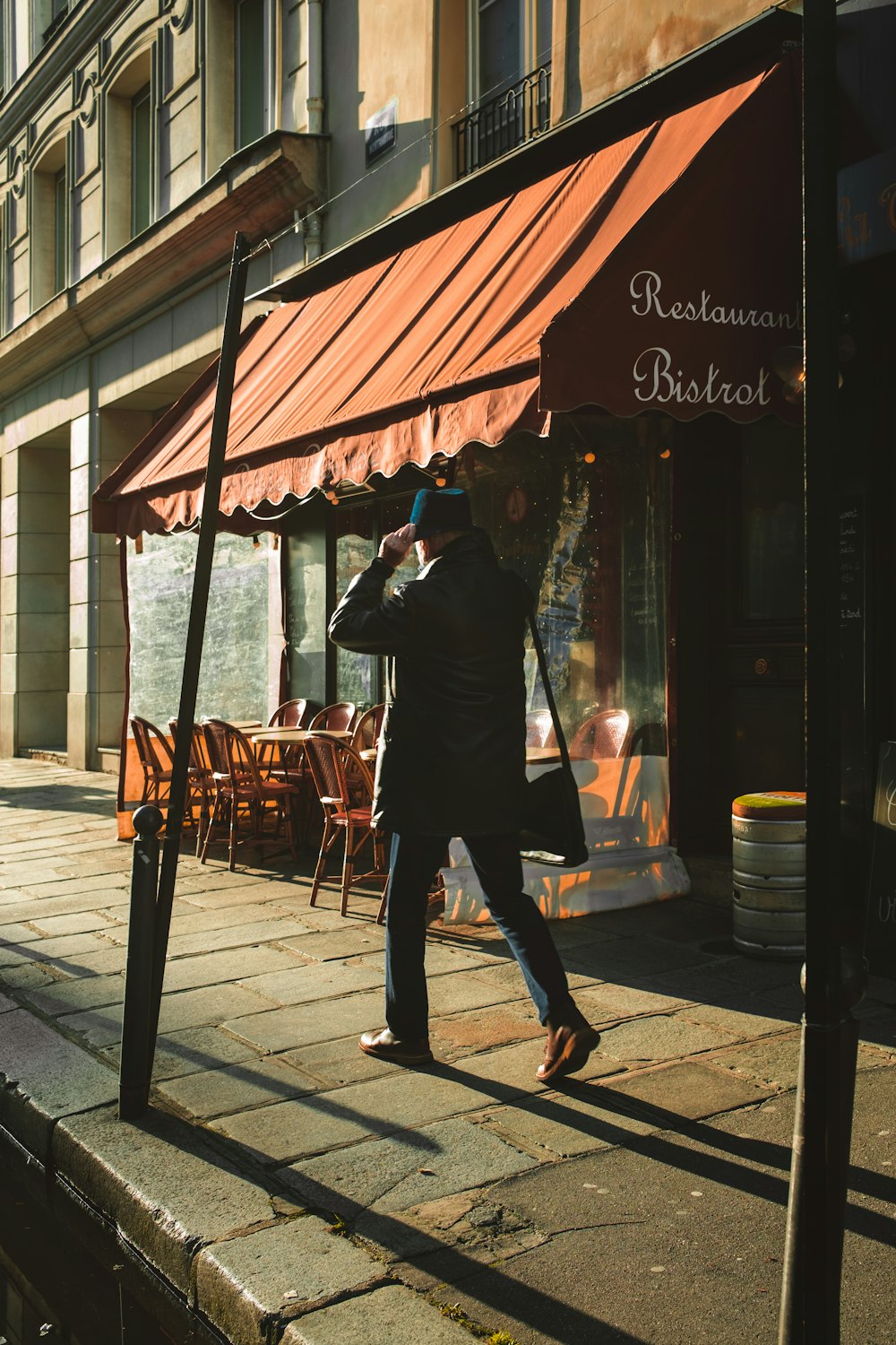 a man walking down a street past a restaurant