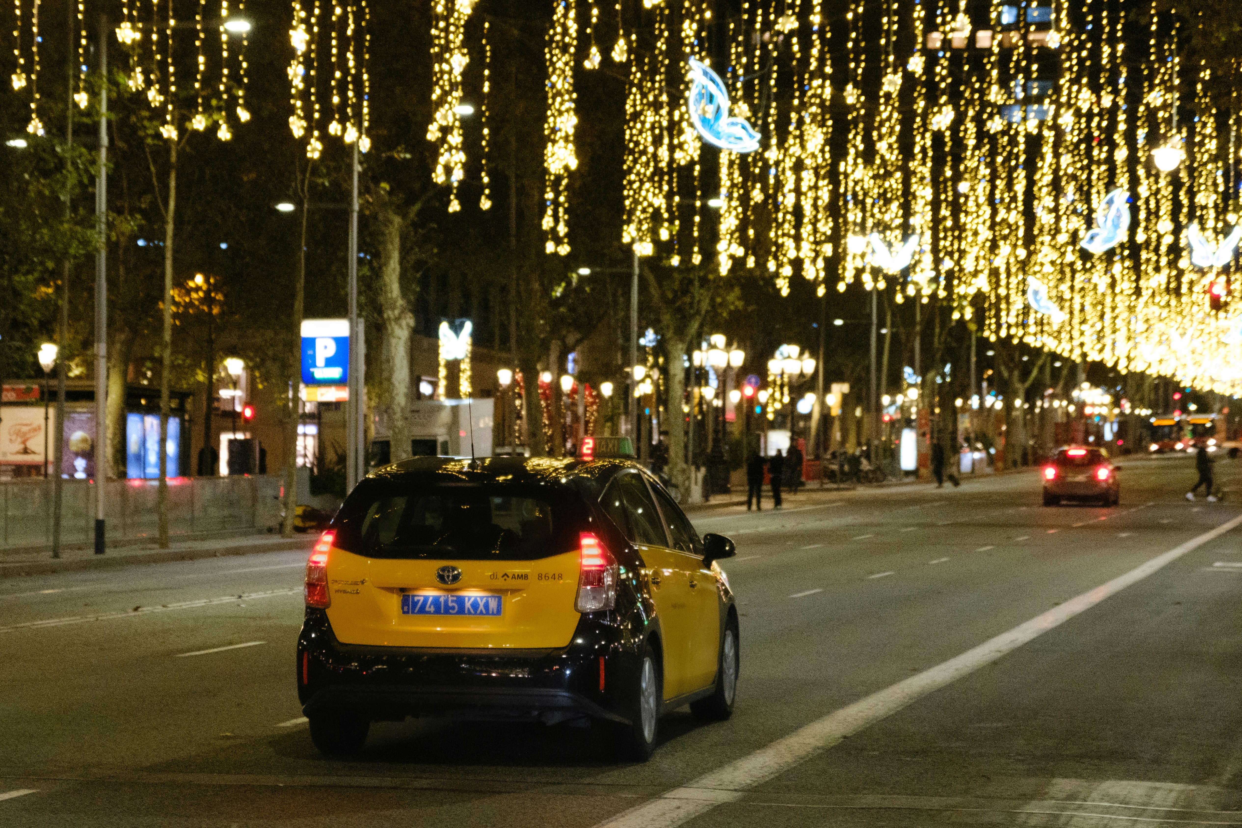 a yellow car driving down a city street at night