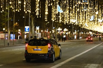 a yellow car driving down a city street at night