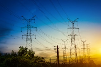 A panoramic view of high-voltage transmission towers stretching across a rural Ontario landscape at sunset.
