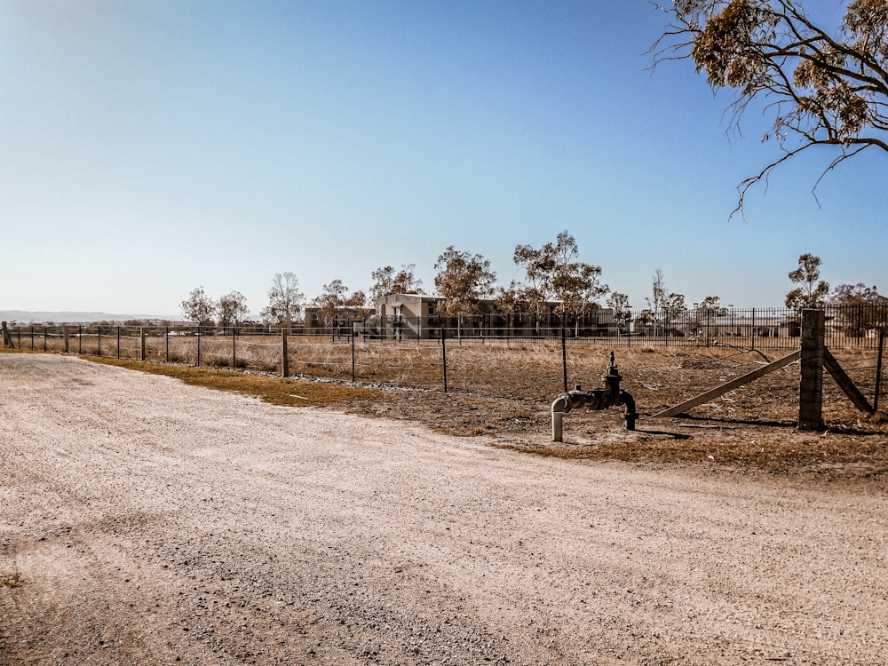 a dirt road with a fence and a fire hydrant