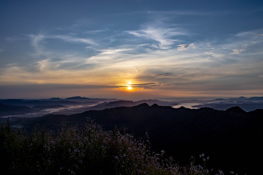 the sun is setting over a mountain range