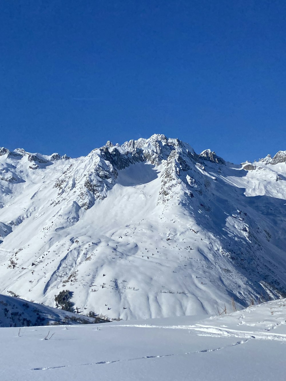 a person on skis standing in the snow in front of a mountain