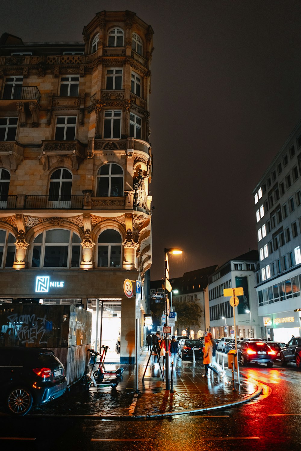 a city street at night with cars parked on the side of the road