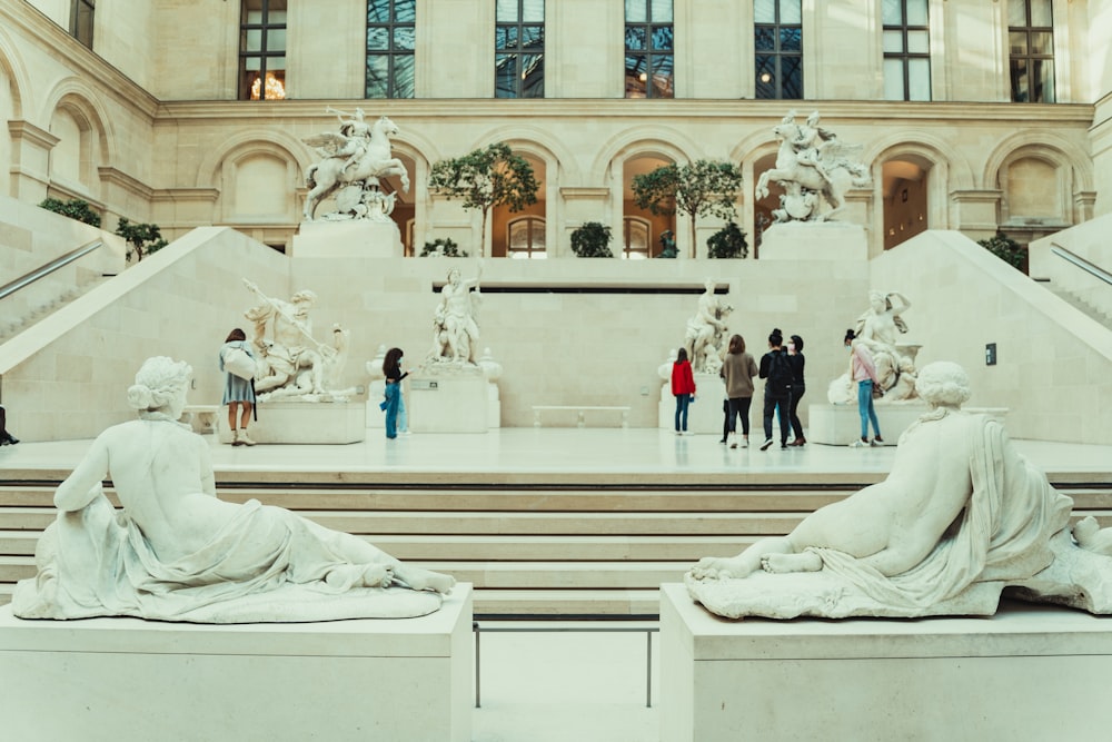 a group of people standing around statues in a building