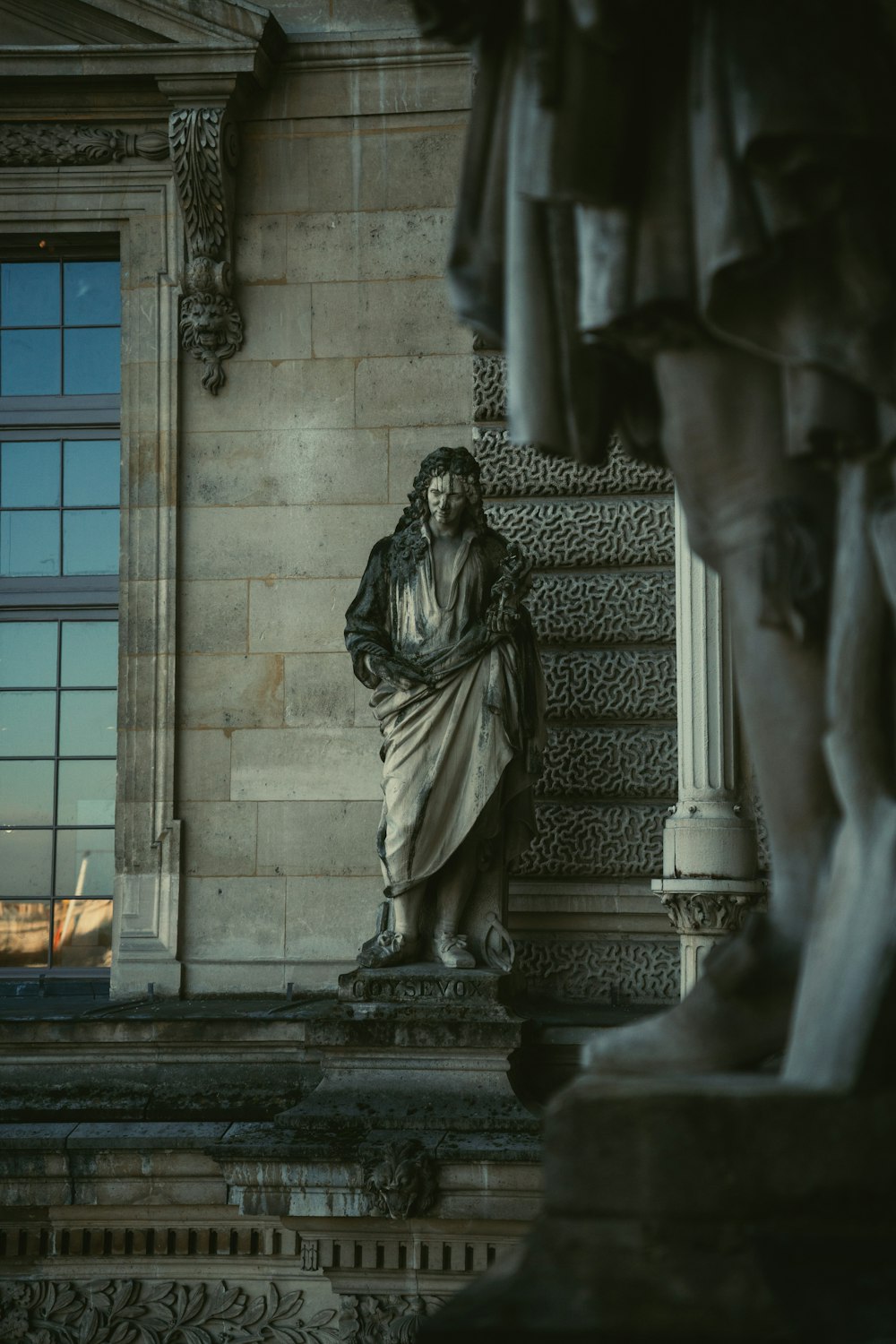 a statue of a man sitting in front of a window