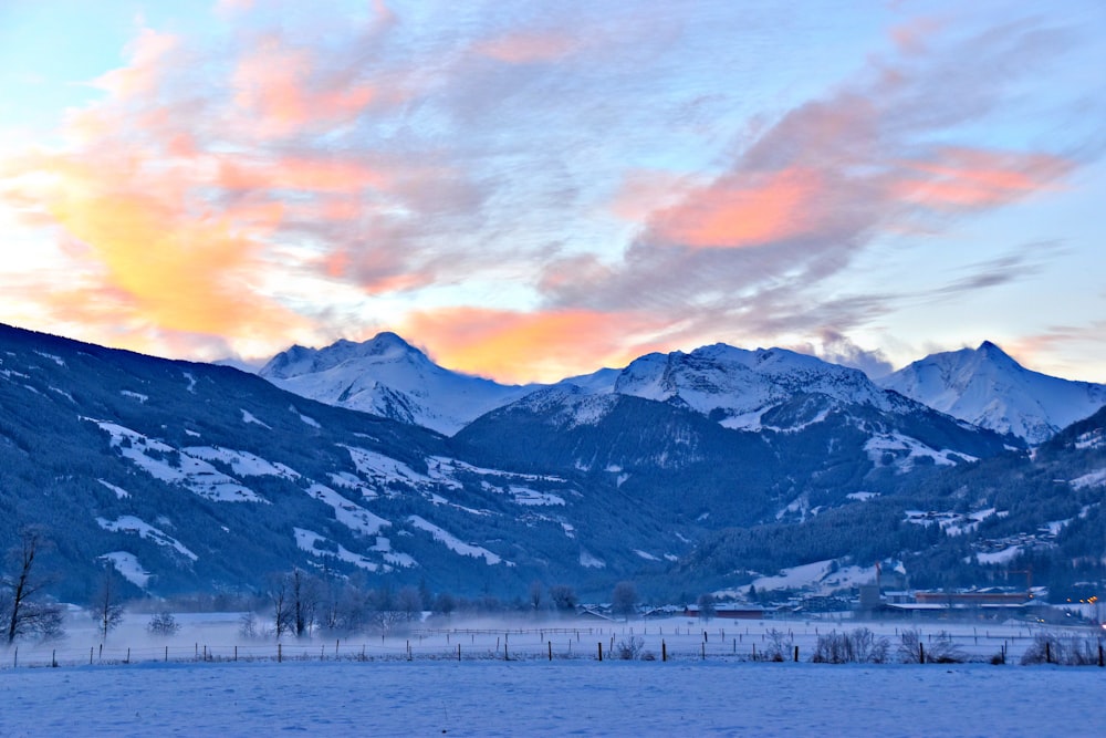 a snow covered field with mountains in the background