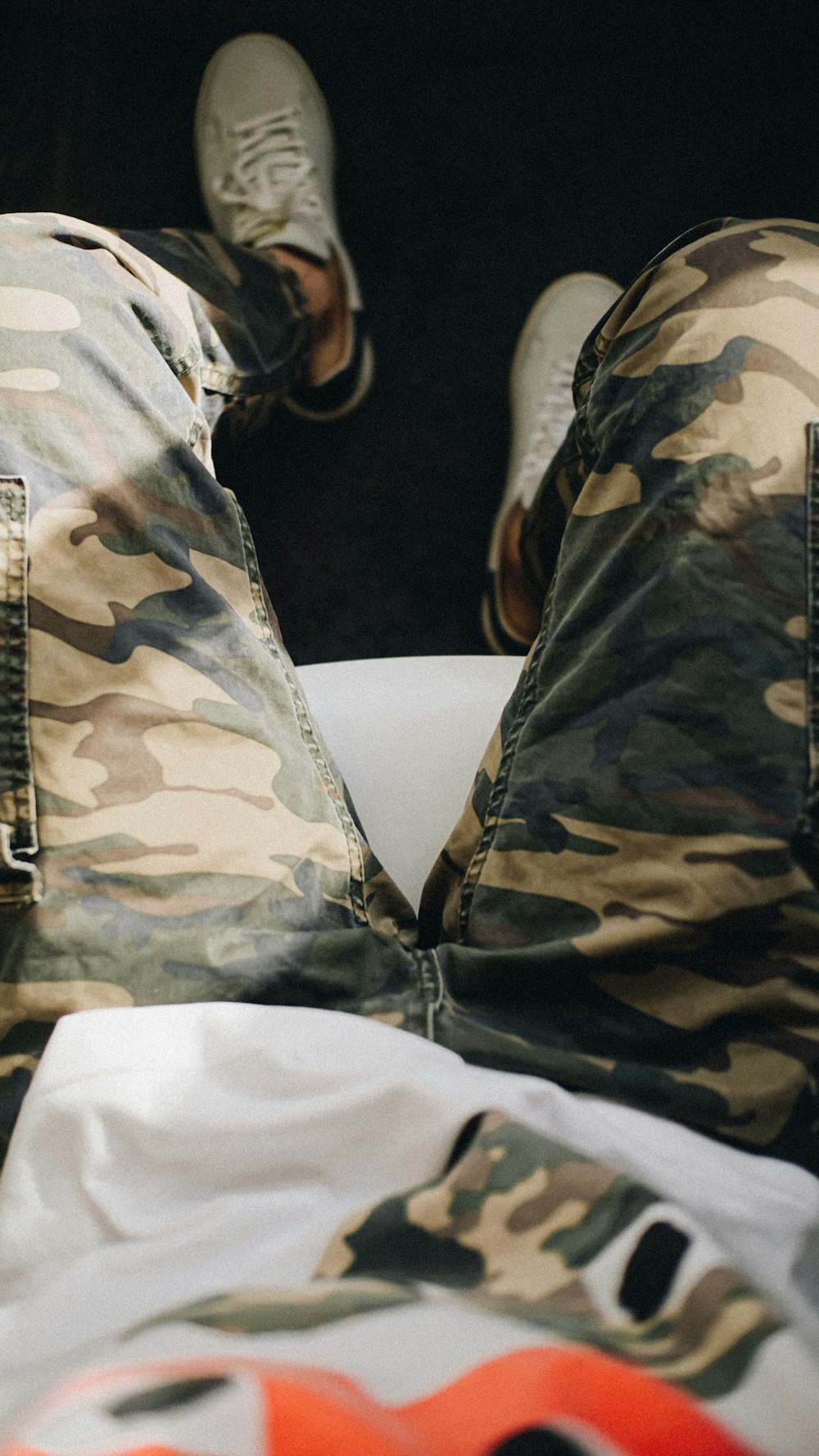 a man in camouflage pants laying on a bed