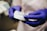 Close-up of a dentist's gloved hands holding a dental impression material in a bright, clean clinic.