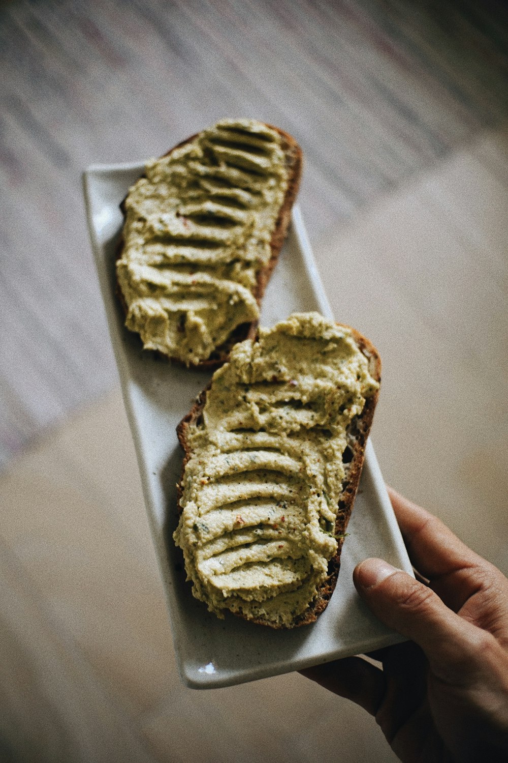 a person holding a plate with two slices of bread