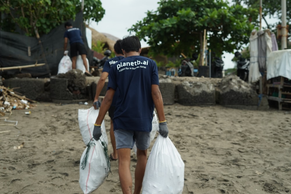 a man carrying two bags of garbage on a beach