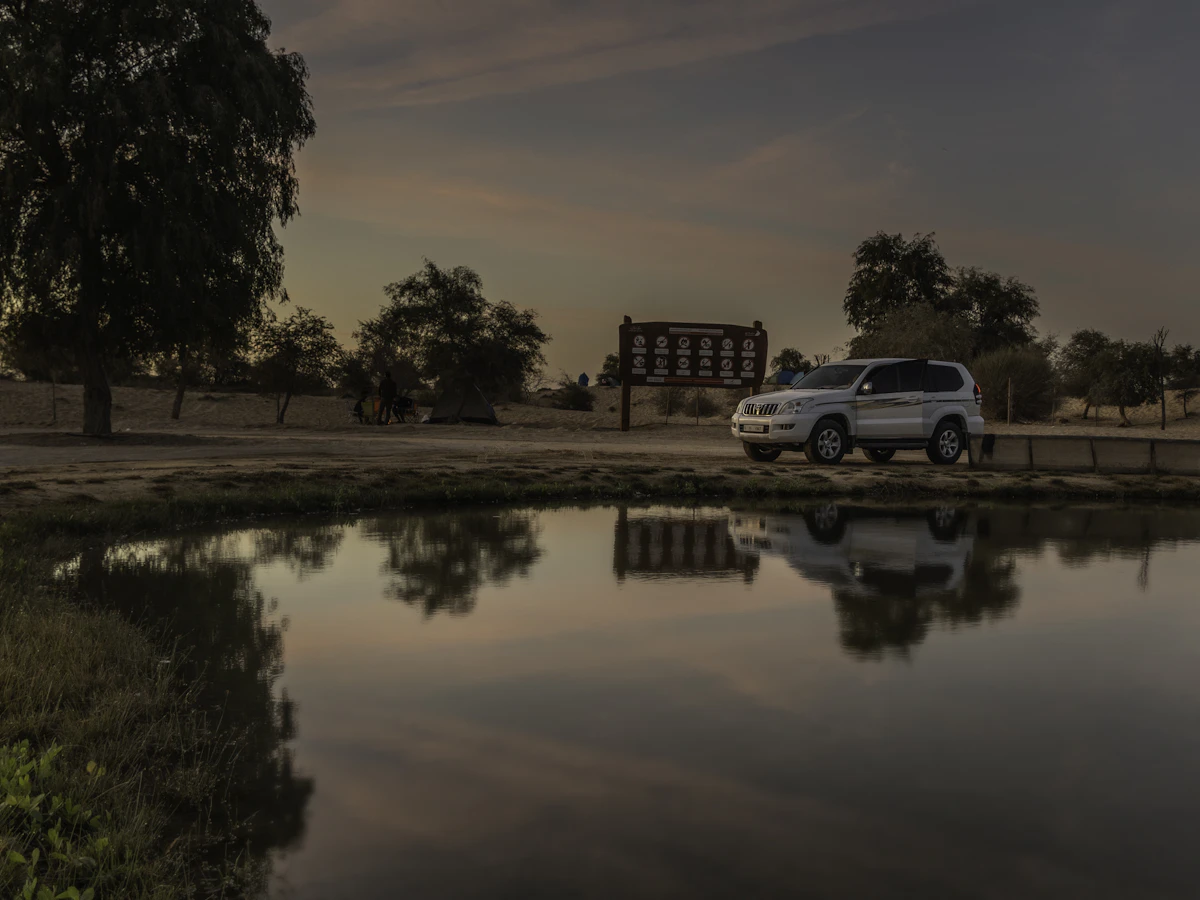 A white van parked next to a body of water at Al Qudra Lake