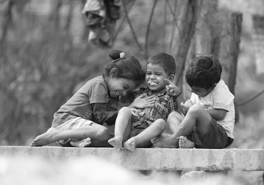 a group of young children sitting on top of a cement wall