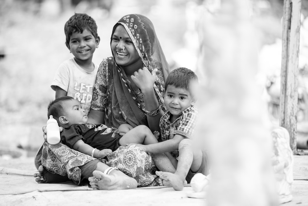 a woman sitting on the ground with two children